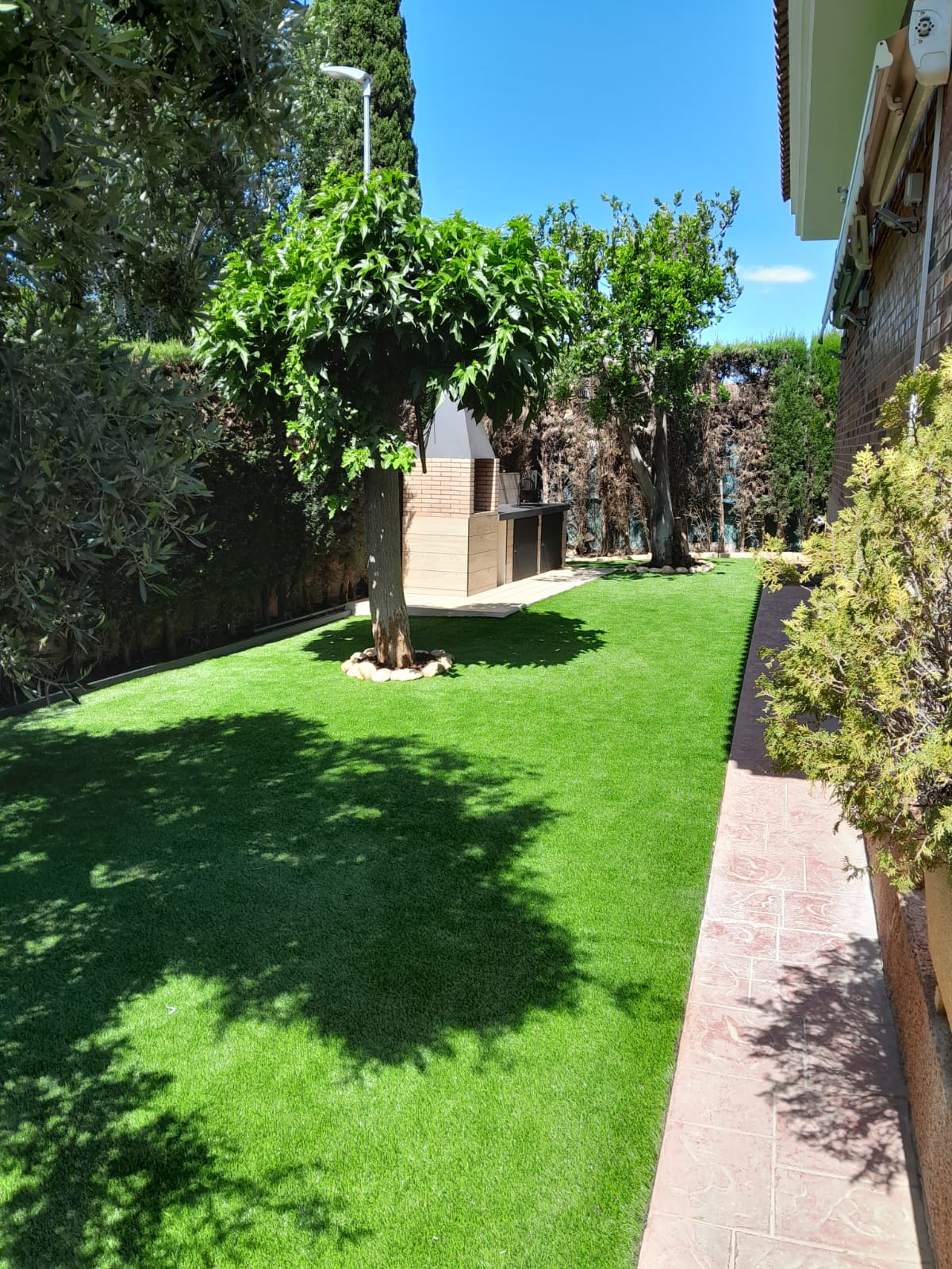 Jardín de césped artificial con barbacoa